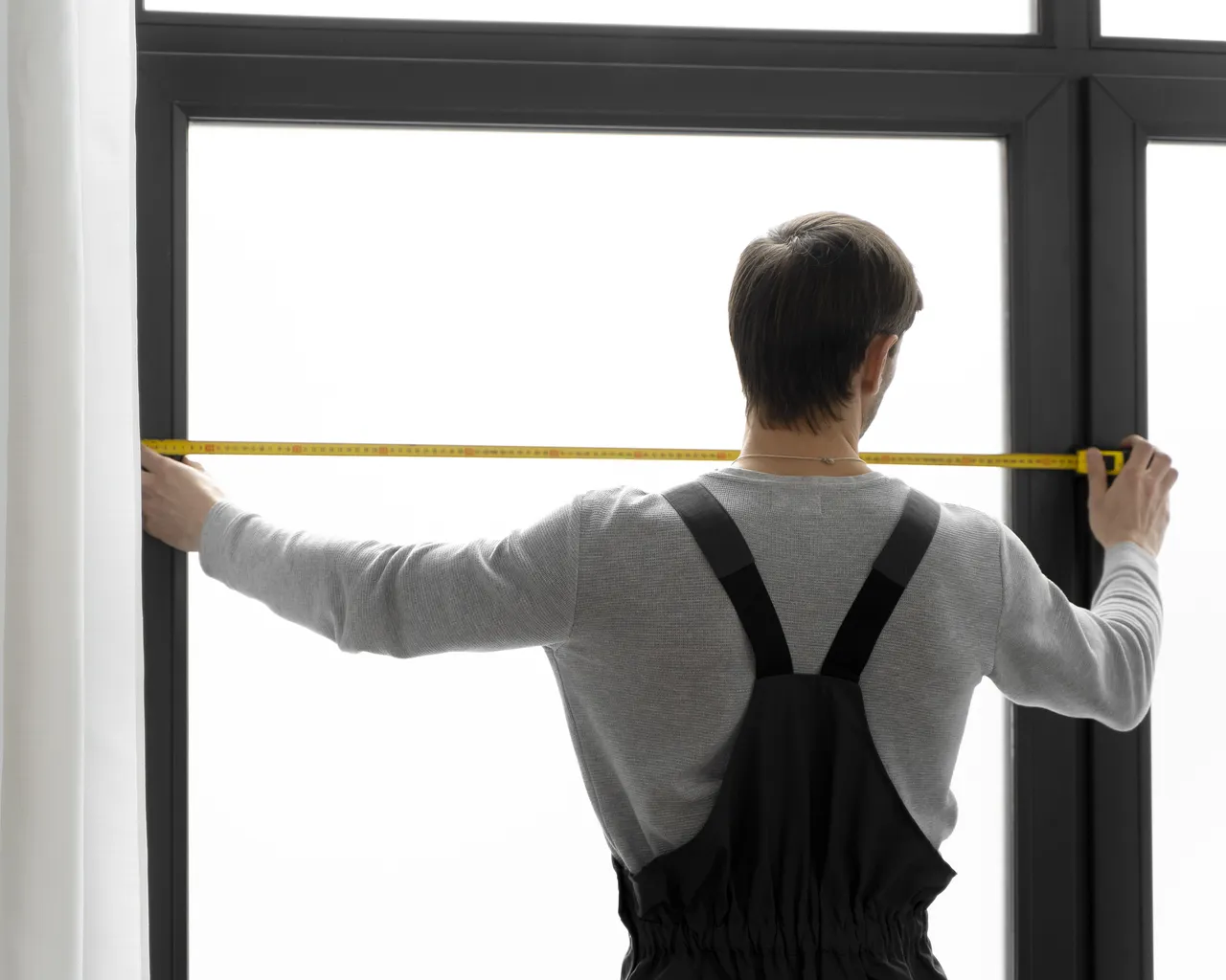 Guy Using Tape Measure On Window
