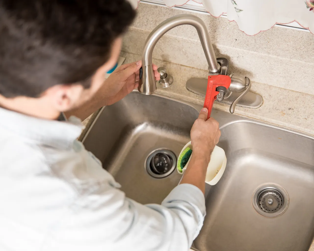 Male Plumber Using Wrench Tighten Water Faucet Kitchen Seen Up Close