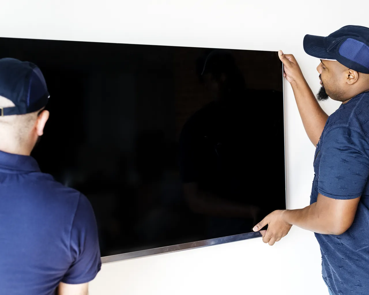 Two Guys Placing Tv On Mount